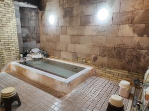 a bathroom with a tub in a brick wall at Hakuba Hotel Hana-no-Sato in Hakuba