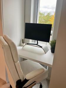 escritorio blanco con monitor de ordenador y silla en Cozy Apartment with Garden & Terrace in Kaunas, en Kaunas