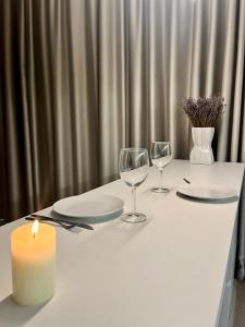 einen weißen Tisch mit Kerzen, Tellern und Gläsern in der Unterkunft Cozy Apartment with Garden & Terrace in Kaunas in Kaunas