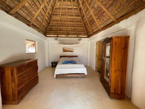 1 dormitorio con cama y techo de madera en Chez Peter Pan Anakao en Anakao