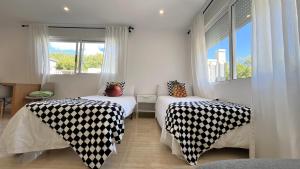 Habitación con 2 camas y colchas en blanco y negro en Kiwidestiny Alicante, en San Juan de Alicante