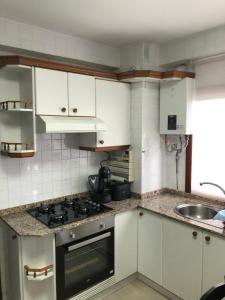 a kitchen with white cabinets and a stove top oven at Piso Negreira in Negreira