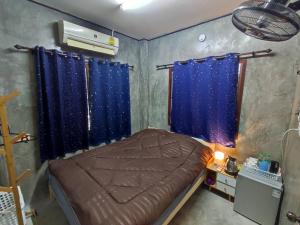 um quarto com uma cama e uma janela com cortinas azuis em BaanNakanoHomestay em Mae Rim