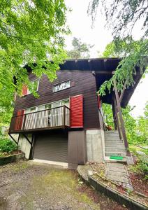 a house with a red door and a balcony at Snowood Chalet Hakuba in Hakuba