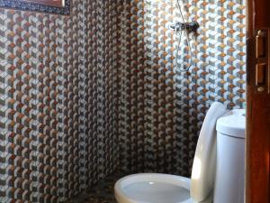 a bathroom with a toilet and a patterned wall at Sweet Homestay in Sidemen