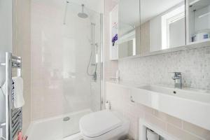 a white bathroom with a toilet and a sink at GuestReady - Chic Urban Haven in Walworth in London