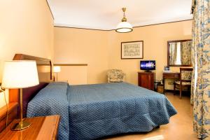 1 dormitorio con cama azul y escritorio en Albergo Reggio, en Reggio Emilia
