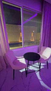 a purple room with two chairs and a table and a window at شاليهات توليب in Sabt Alalayah