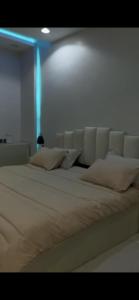 a bedroom with a white bed with a blue light at شاليهات توليب in Sabt Alalayah