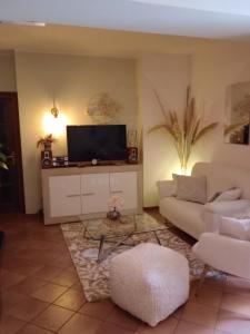 sala de estar con sofá blanco y TV en La Fontanella, en Spello