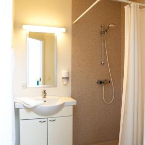 a bathroom with a sink and a shower with a mirror at Hotel Havlund Bed and Breakfast in Grenå