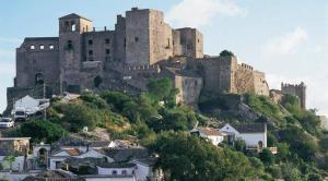 um grande castelo no topo de uma colina com casas em Balcon de los Amorosos em Castellar de la Frontera