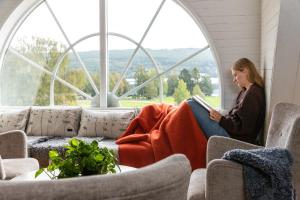 Eine Frau, die in einem Fenster sitzt und ein Buch liest. in der Unterkunft STF Undersvik Gårdshotell & Vandrarhem in Vallsta