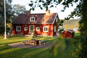 ein rotes Haus mit Picknicktischen davor in der Unterkunft STF Undersvik Gårdshotell & Vandrarhem in Vallsta