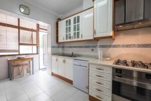 a kitchen with white cabinets and a stove top oven at Apart Lisboa confortavel 2 quartos com terraço in Odivelas