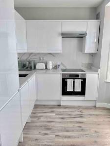 una cucina con armadi bianchi e forno nero di Private Luxury One Bedroom Apartment with parking a Palmers Green