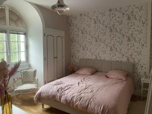 Schlafzimmer mit einem Bett mit rosa Bettwäsche und einem Stuhl in der Unterkunft Le Bois Perrin in Joinville