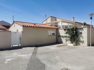 a white house with a parking lot with a garage at Calme et sérenité in Le Barcarès