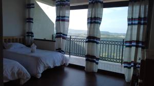 a bedroom with two beds and a balcony with windows at Amba Lodge Lalibela in Lalibela