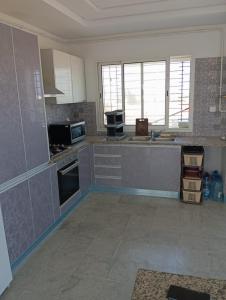 a kitchen with gray cabinets and appliances in a room at Zone touristique mahdia en face clinique rahma in Mahdia