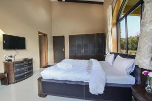 a bedroom with a large bed and a television at Akbar Villa 4BHK With Pool in Lonavala +36 photos