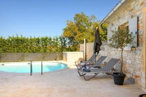 a patio with chairs and an umbrella next to a pool at Villa Onelia by IstriaLux in Vodnjan