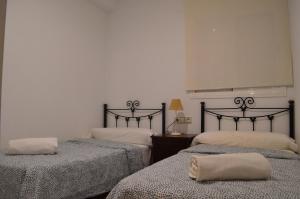 a room with two beds with blankets and a lamp at Las Arenas-Islantilla-Huelva in Islantilla