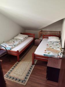 two beds in a small room with wooden floors at Apartmani Jaguzovic in Mrkonjić Grad