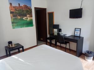 a bedroom with a bed and a desk with a computer at Hôtel Restaurant Le Relais de l'Estuaire in Étauliers