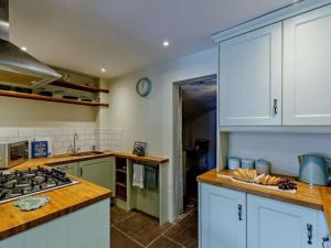 a kitchen with white cabinets and a stove top oven at Beautiful 2 Bedroom Riverside Cottage in Bridgnorth
