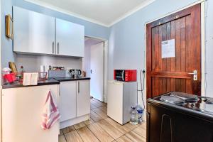eine Küche mit weißen Schränken und einer Holztür in der Unterkunft Lonehill Arnheim- Cottage 1 in Sandton + 5 Fotos