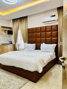 a bedroom with a large bed with a brown headboard at Diaggello Homex Apartment in Lekki