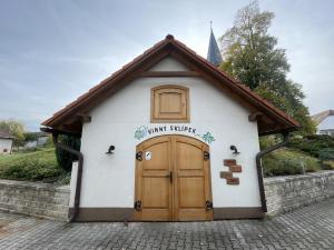 a small white building with a wooden door at Penzion a restaurace U Nováků in Bítovany