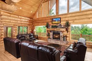 a living room with leather furniture and a fireplace at Big Bear Ridge Lodge - Breathtaking mountain views and private forest scenes in amazing large log cabin in Gatlinburg