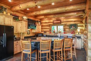 a kitchen with wooden cabinets and a black refrigerator at Big Bear Ridge Lodge - Breathtaking mountain views and private forest scenes in amazing large log cabin in Gatlinburg