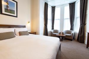 a hotel room with a large bed and windows at The Grosvenor Plymouth in Plymouth