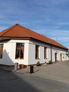 biały budynek z czerwonym dachem na ulicy w obiekcie Penzion a restaurace U Nováků w mieście Bítovany
