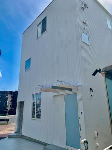 een wit gebouw met een deur aan de zijkant bij Villa Monica EAST in Nagoya