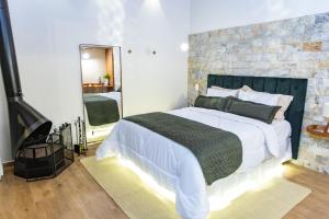 a bedroom with a large bed and a brick wall at Chalés Quinta da Boa Vista in São Bento do Sapucaí