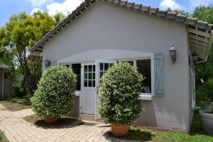 une maison blanche avec deux buissons devant elle dans l'établissement Lonehill - Standard 2 Guest Suite - Suite 1B, à Sandton