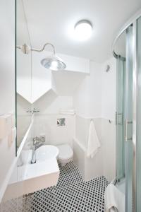 a white bathroom with a sink and a toilet at Monte Cassino in Sopot