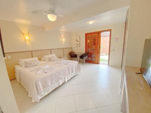 a bedroom with a white bed and a table and chairs at Pousada Montemar in Ilhabela
