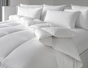Cama blanca con sábanas y almohadas blancas en Citrea Santander, en Santander