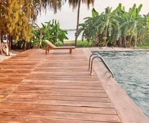 a wooden walkway with a bench on top of the water at Gîte du Lac in Niaga