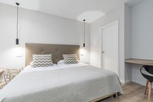 a white bedroom with a large bed with two pillows at Smartr Las Palmas in Las Palmas de Gran Canaria