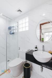 a white bathroom with a sink and a toilet at HoLo Central Hanoi - Serviced HomeStay in Hanoi