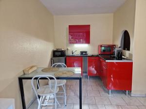 蒂爾凱姆的住宿－les griffes d'or，厨房配有红色橱柜和桌椅