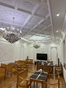 une salle à manger avec tables et chaises et un lustre dans l'établissement Hotel POYI KALON terrace حلال, à Boukhara