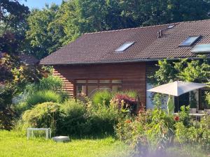 a small house with an umbrella in the yard at Tu Casa Chiemsee Ferienhaus in Gstadt am Chiemsee