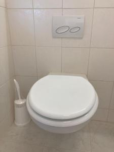 a white toilet in a bathroom with a toilet brush at Tu Casa Chiemsee in Gstadt am Chiemsee